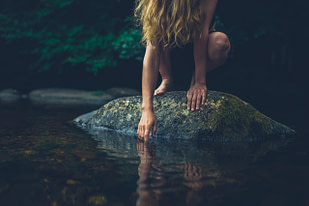 Young woman sitting on rock in a river